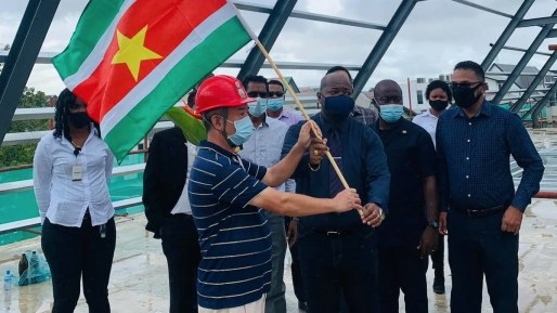Bij het bereiken van dit hoogtepunt zijn de Surinaamse vlag en een bloemstuk aan het bouwwerk vastgemaakt. Foto: DNA Bij het bereiken van dit hoogtepunt zijn de Surinaamse vlag en een bloemstuk aan het bouwwerk vastgemaakt. Foto: DNA